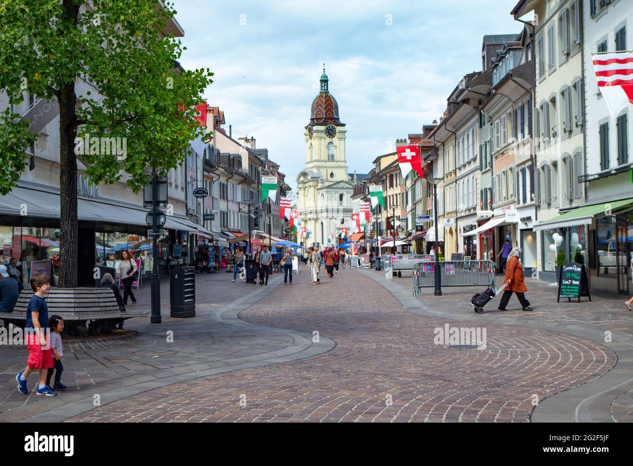 Morges, Schweiz - 19. Juni 2020: Belebte Fußgängerzone mit Kirche Stockfoto