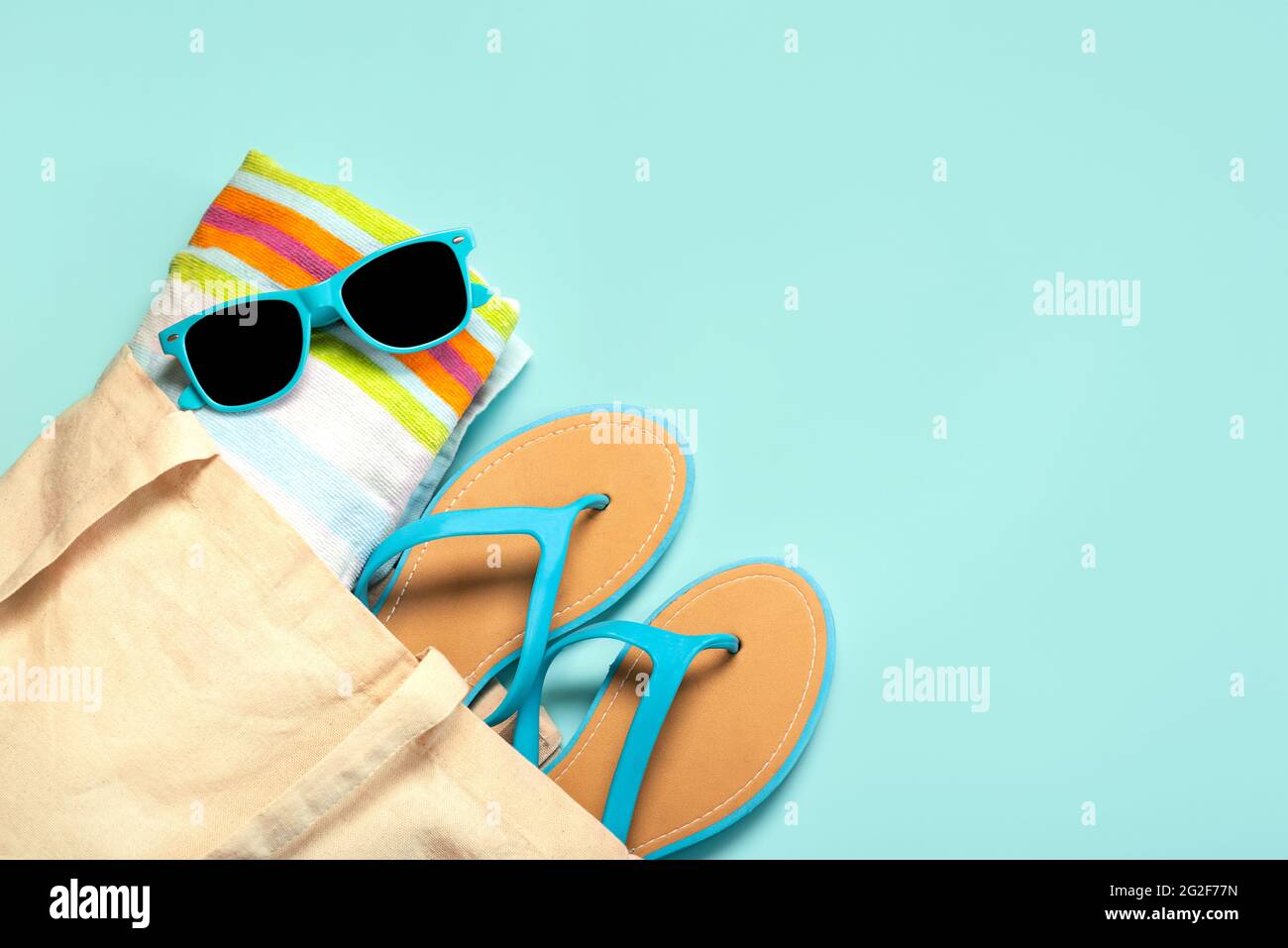 Sommerferienkonzept.Draufsicht auf blaue Flip Flops, Strandtuch, blaue Sonnenbrille und Strandtasche mit Kopierplatz auf blauem Hintergrund Stockfoto