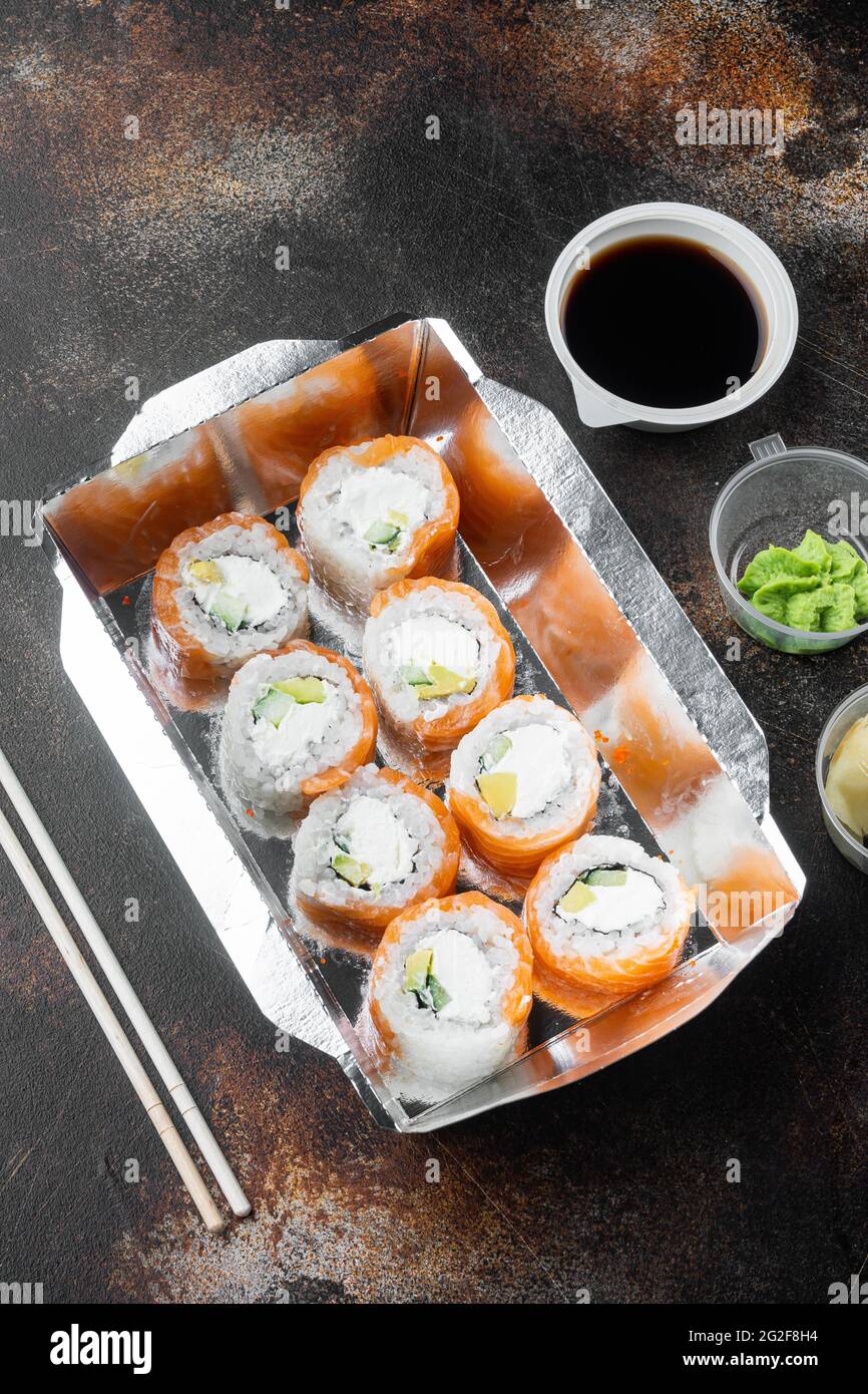Leckere Sushi-Rollen in Einwegkisten-Set, auf altem dunklen rustikalen Hintergrund Stockfoto