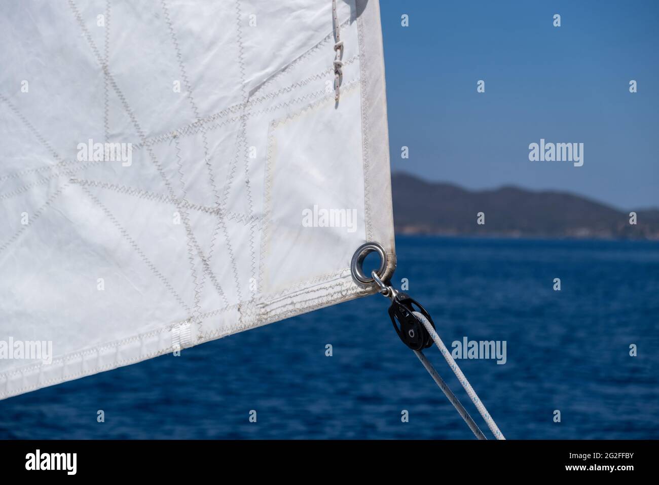 Segeldetails, Öse und Seil in Nahaufnahme. Yacht segelt im offenen ruhigen Ozean Hintergrund. Freizeitangebot, Reise- und Transportkonzept. Stockfoto