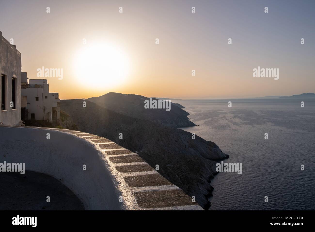 Insel Folegandros bei Sonnenuntergang. Kykladen, Griechenland. Atemberaubende Aussicht über die Ägäis von den hohen Klippen im Dorf chora, Sonne scheint auf orange Himmel Stockfoto