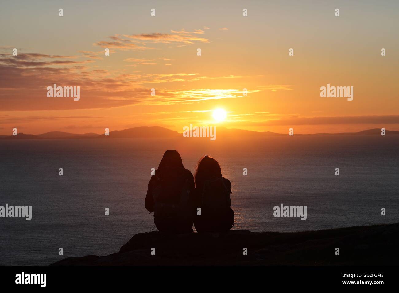 Zwei Menschen beobachten den Sonnenuntergang in der Nähe von Neist Point, Isle of Skye, Schottland, Großbritannien. Stockfoto