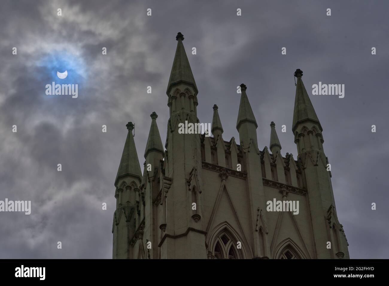 Partielle Sonnenfinsternis wie in Glasgow Scotland am 10/06/2021 Trinity Tower im Vordergrund mit dramatischem Himmel und blauem Fleck durch die Sonne. Stockfoto