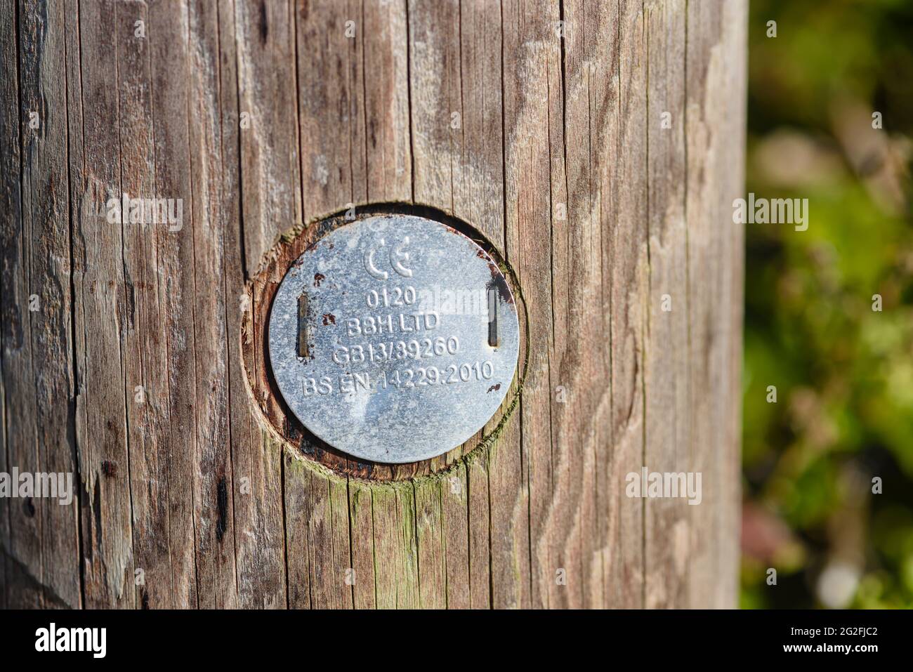 Metalltafel mit CE-Kennzeichnung auf einem hölzernen Telegrafenmast, der anzeigt, dass er die EU-Vorschriften für Sicherheit, Gesundheit und Umweltschutz erfüllt Stockfoto