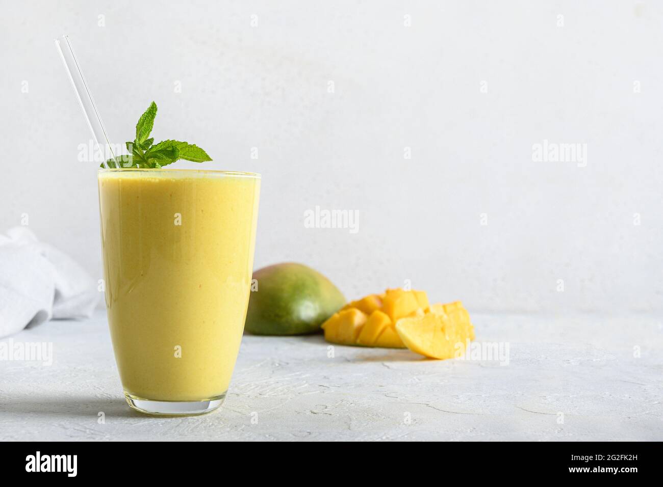 Mango-Lassi-Garnitur Minze auf weißem Hintergrund. Indisches gesundes ayurvedisches Getränk mit Mango. Speicherplatz kopieren. Frische Lassi aus Joghurt, Wasser, Gewürzen, Fr. Stockfoto
