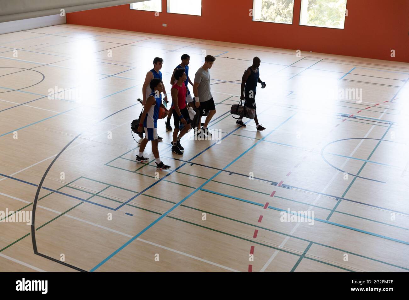 Verschiedene männliche Basketballteams und Trainer verlassen das Fitnessstudio nach dem Spiel Stockfoto