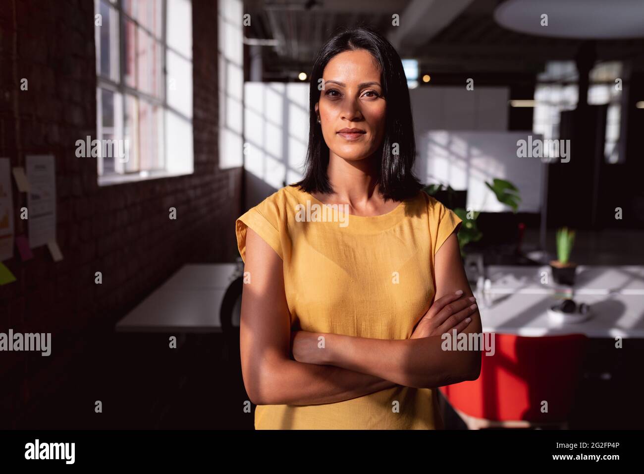 Porträt einer kaukasischen Geschäftsfrau, die im sonnigen Büro steht und zur Kamera schaut, mit Schatten im Gesicht Stockfoto