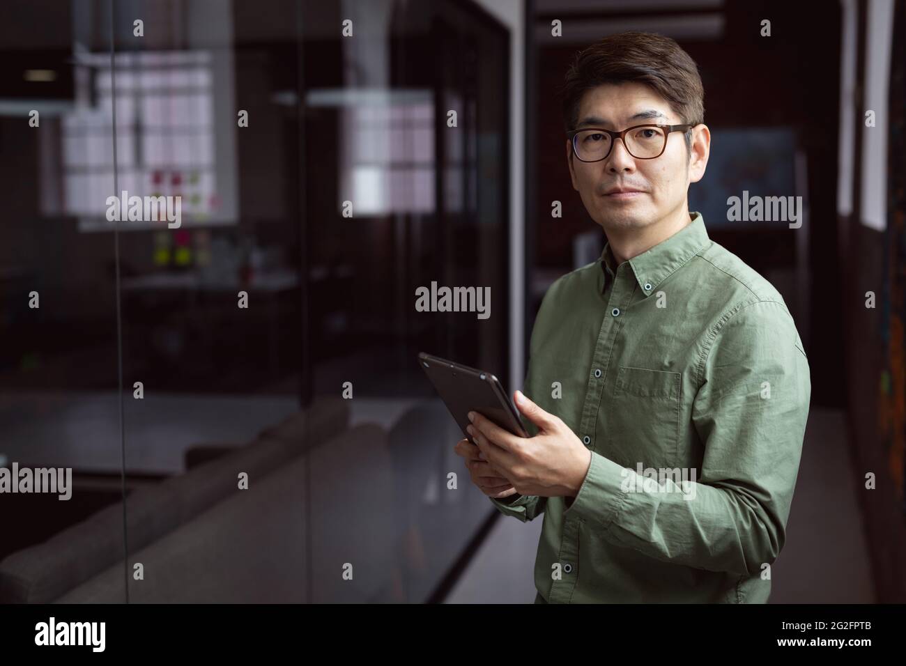 Porträt eines asiatischen Geschäftsmannes, der in einem leeren Büro mit Tablet steht Stockfoto