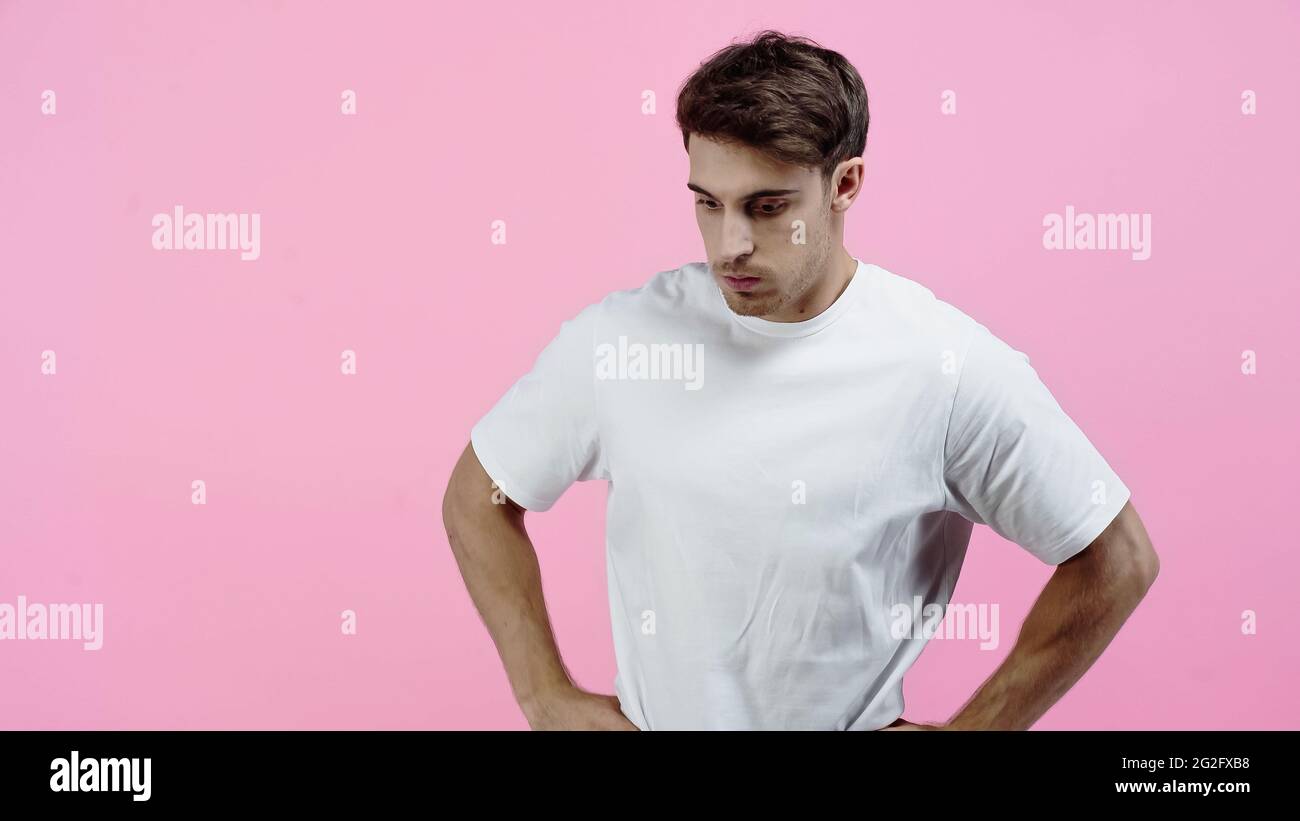 Nachdenklicher Mann im weißen T-Shirt, isoliert auf Rosa stehend Stockfoto