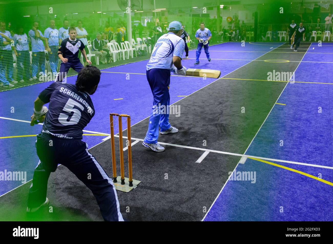 Batsman hinterlässt bei einem Spiel von Indoor Cricket eine Lieferung auf der Beinseite Stockfoto
