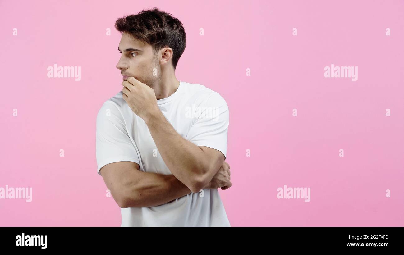 Brünett Mann in weißem T-Shirt schaut weg isoliert auf rosa Stockfoto