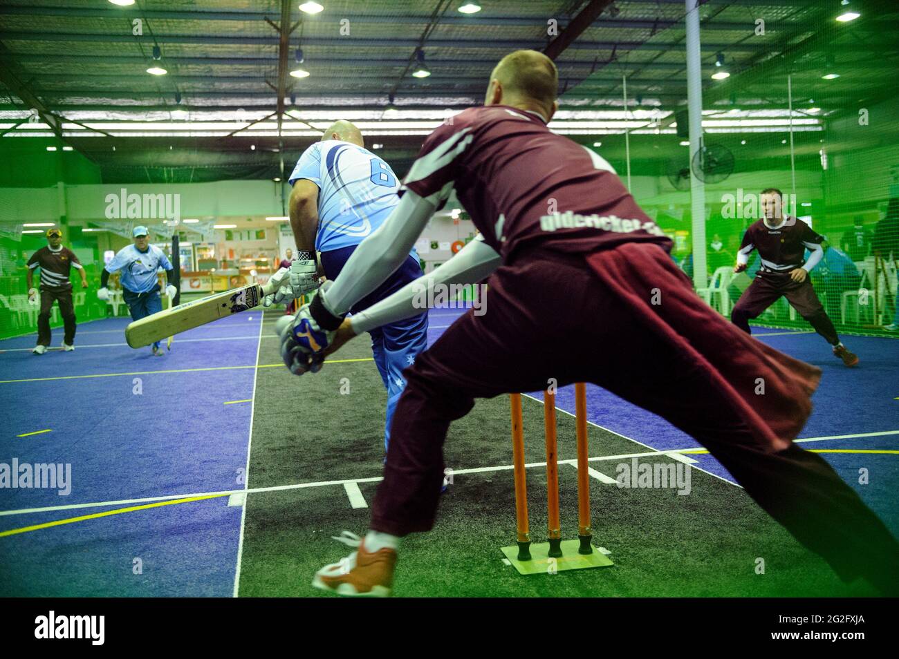 Wicketkeeper nimmt während eines Spiels von Indoor Cricket eine Lieferung an den Beinen vor Stockfoto