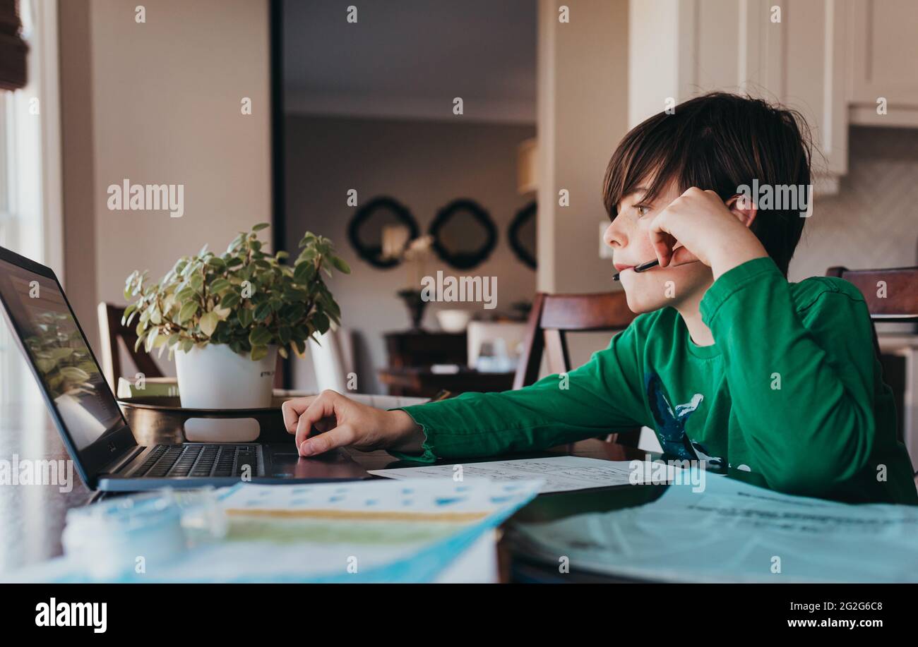 Junge tun auf der Schule Arbeit online am Computer am Küchentisch. Stockfoto