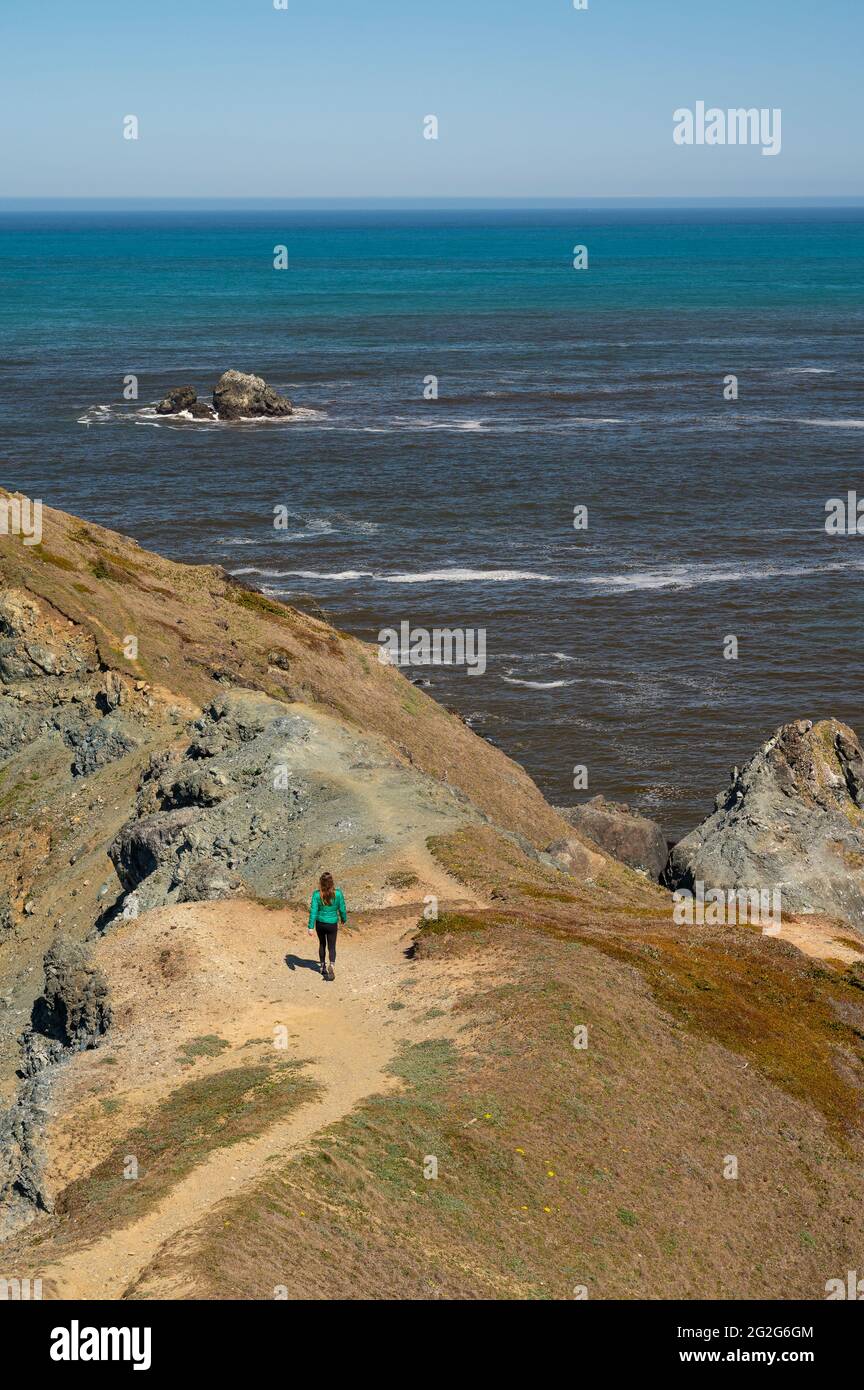 Weibliche Wandererin Im Green Puffy Coat Wanderweg, Der Zum Meer Führt Stockfoto