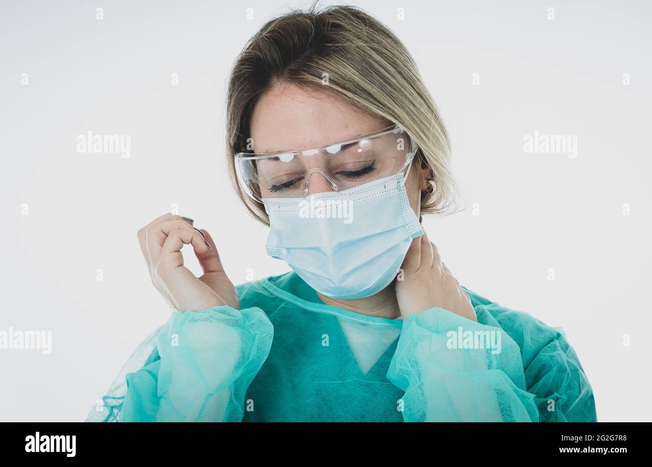 Traurige und überforderte Ärztin oder Krankenschwester, die eine schützende Gesichtsmaske trägt. Depressive und müde Arbeit auf der Intensivstation mit Coronavirus-Patienten. Stockfoto