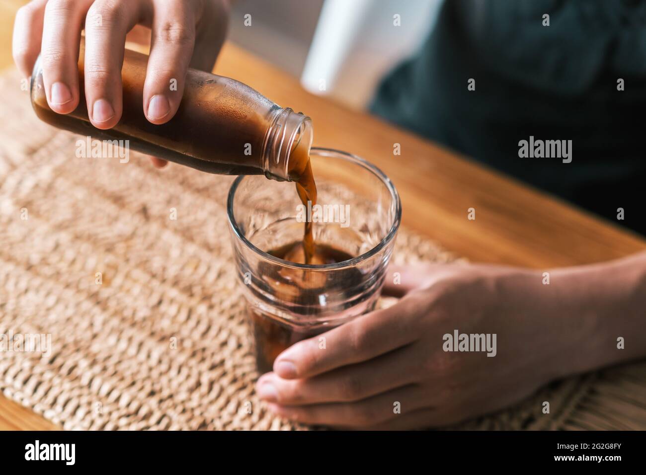 Gießen Sie eiskalten Brühkaffee aus der Flasche in das Glas Stockfoto