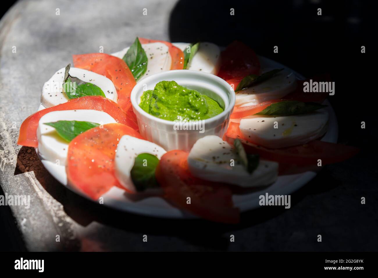 Caprese Salat auf einer Betonoberfläche mit Spinat Pesto Stockfoto
