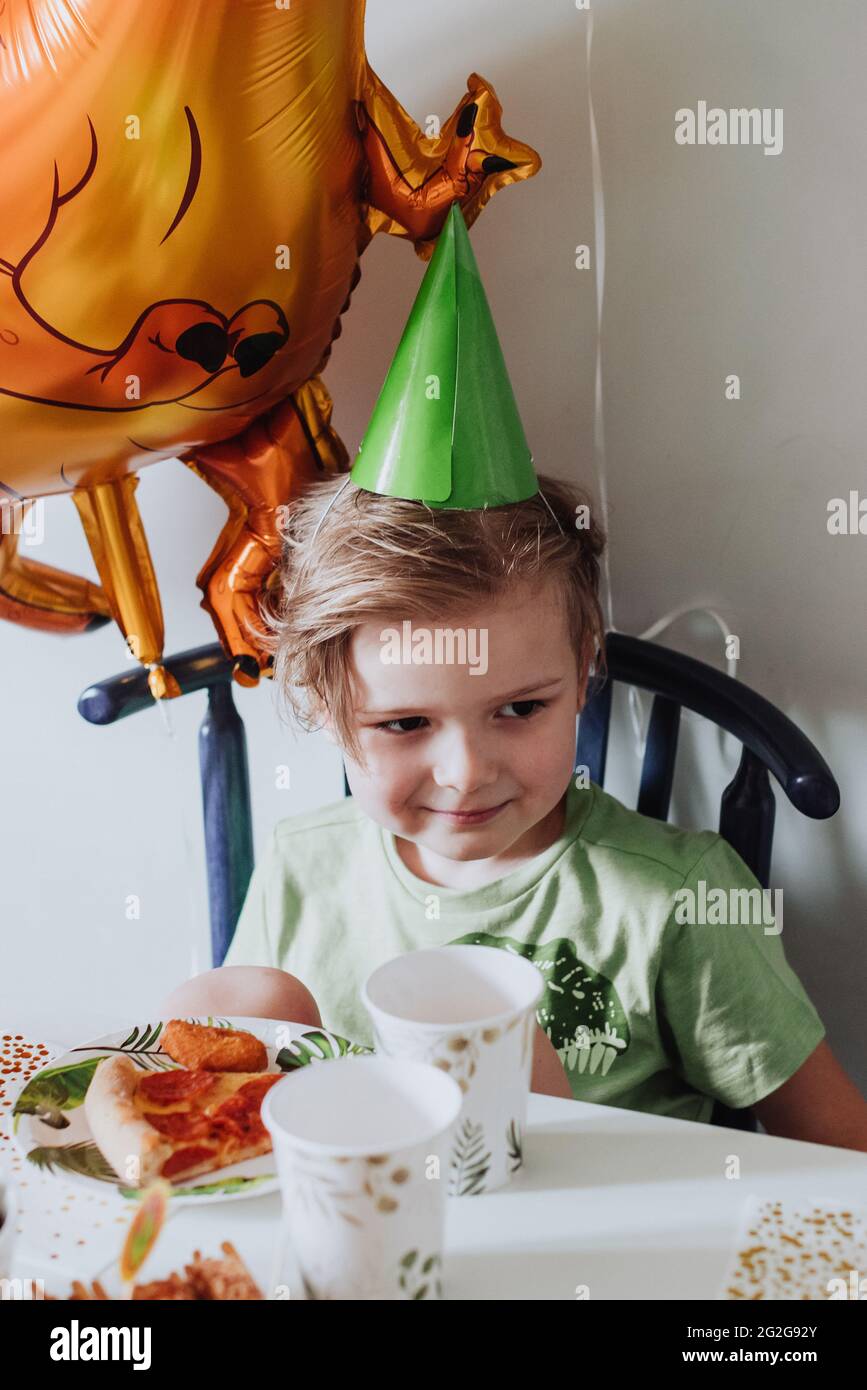 5 Jahre Junge, der in seinem Zimmer spielt, grünes T-Shirt mit Dinosaurier-Print trägt und Geburtstag hat Stockfoto