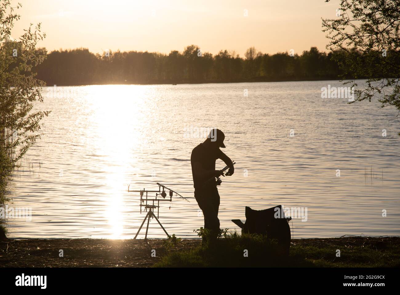 Eine Fischersilhouette beim Fischen bei Sonnenuntergang. Stockfoto