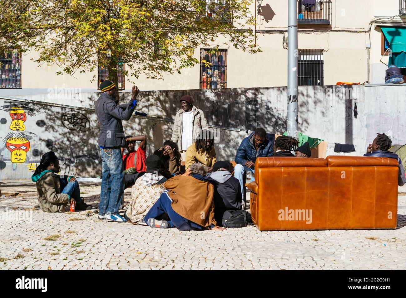 Gruppe von Einwanderern, die auf einem Platz chatten. Lavapiés ist ein historisches Viertel in der Stadt Madrid. Jetzt hat es die große Einwandererbevölkerung gegeben Stockfoto