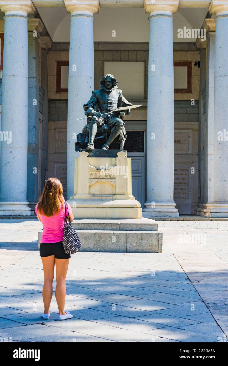 Eine junge Frau schaut auf die Statue des Malers Velazquez neben dem Eingang des Prado Museums. Das Prado Museum - Museo del Prado, offiziell kn Stockfoto