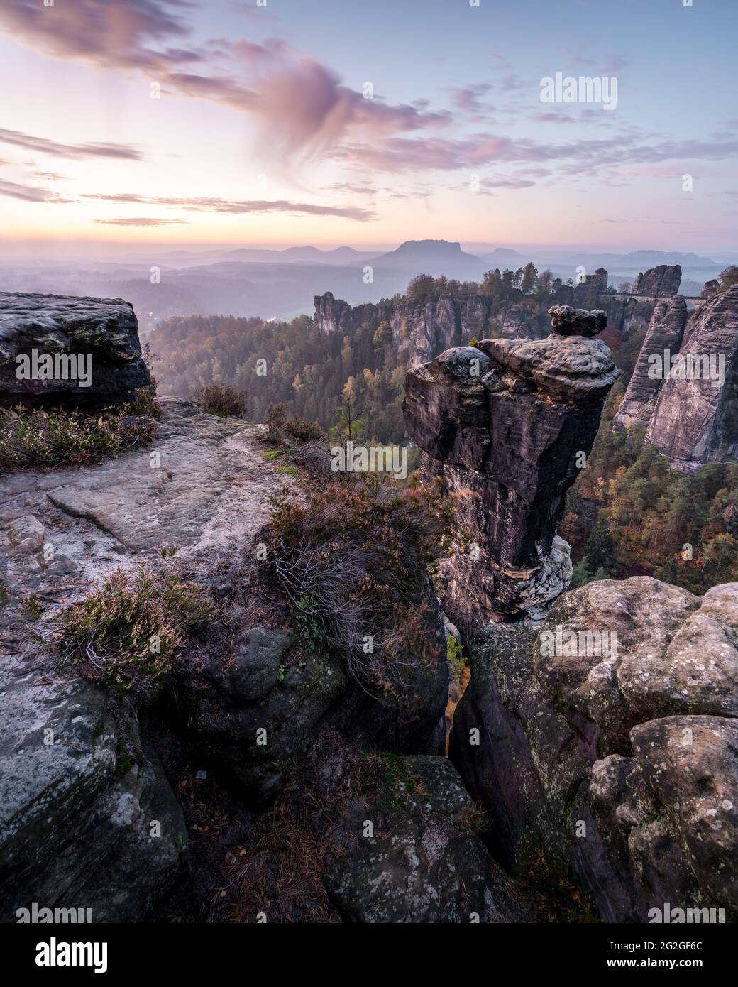 Farbiger Sonnenaufgang hinter der Wehlnadel gegenüber der Bastei-Brücke im Elbsandsteingebirge. Stockfoto