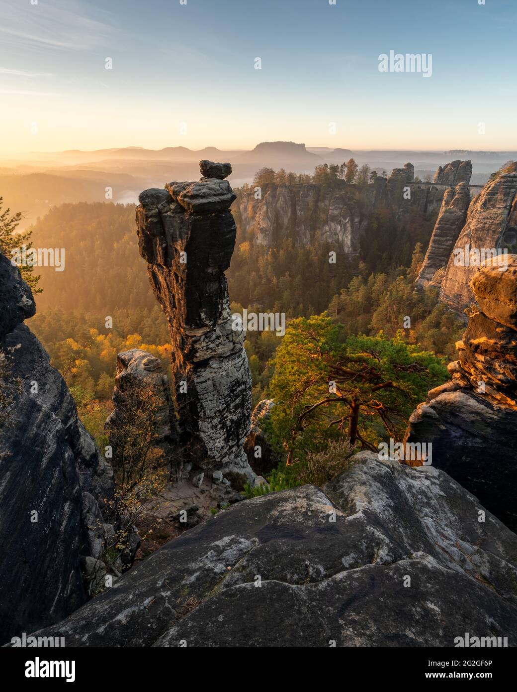 Farbiger Sonnenaufgang hinter der Wehlnadel gegenüber der Bastei-Brücke im Elbsandsteingebirge. Stockfoto