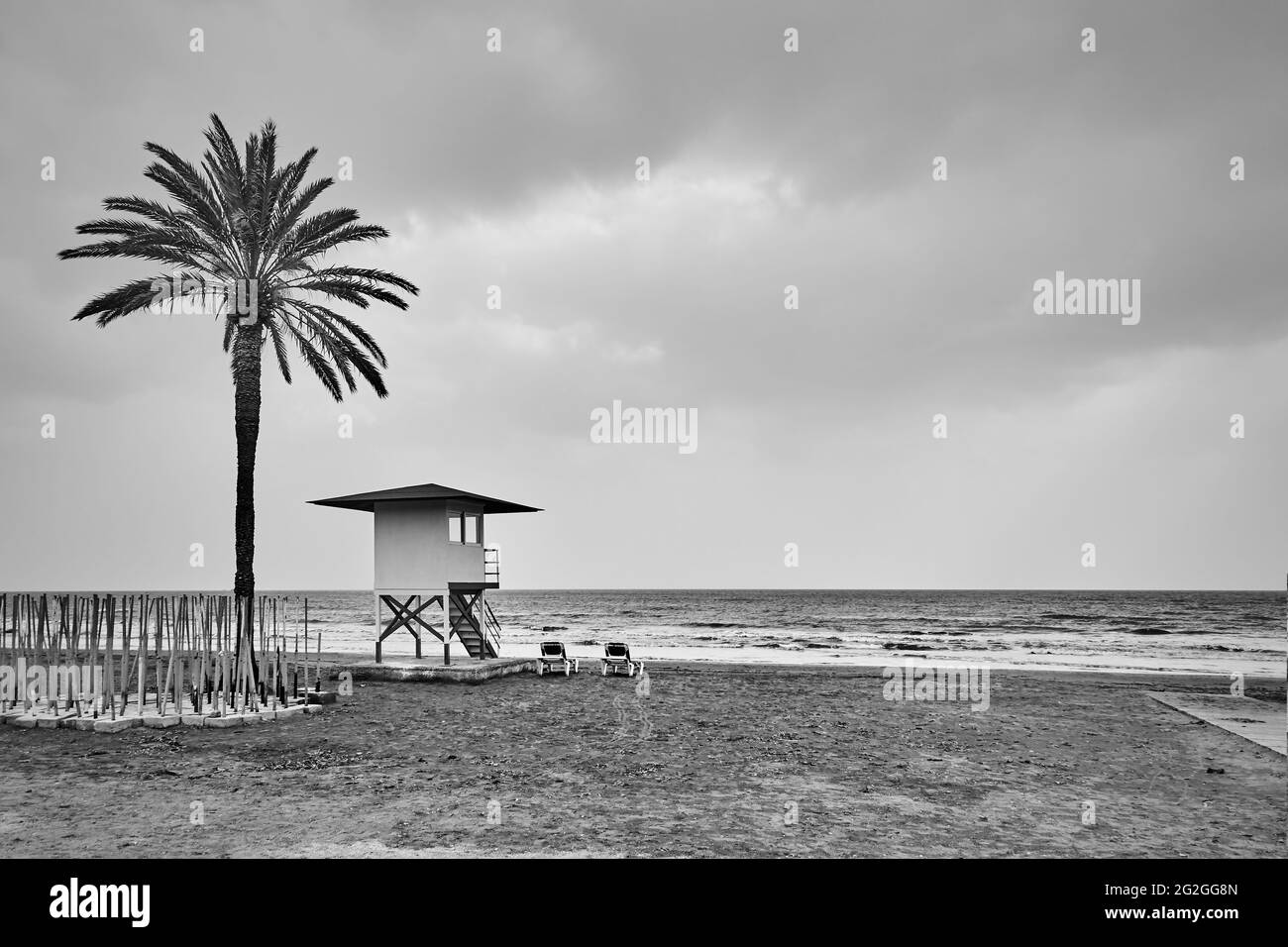 Einsame Strand mit Palmen und Rettungsschwimmer Turm am Meer. Schwarzweiß-Fotografie, Landschaft Stockfoto