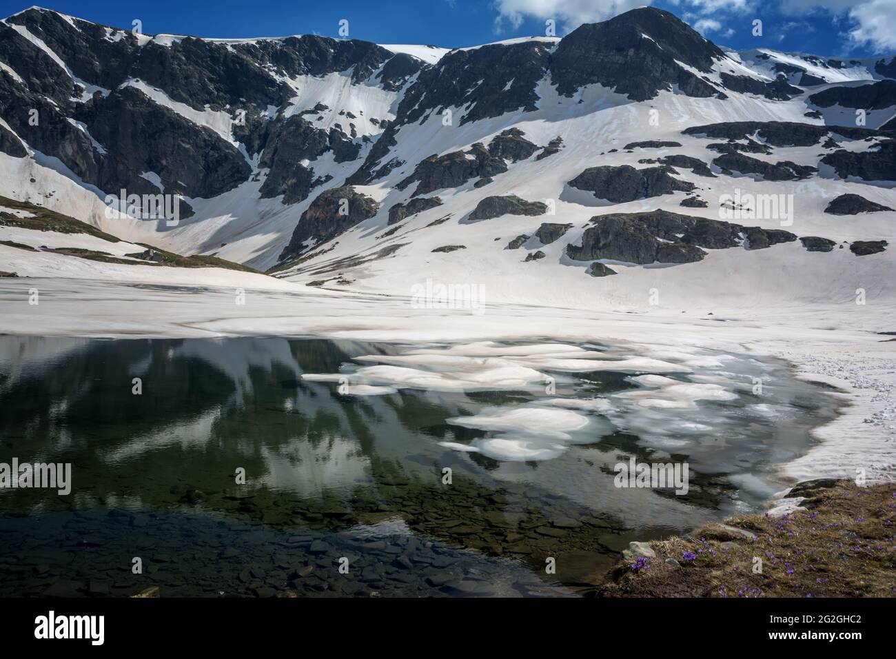 Wunderschöne Berglandschaft im Frühling, Rila-Berg, sieben Rila-Seen, Bulgarien. Gefrorene Gletscherseen vor dem Hintergrund eines hohen felsigen Gipfels Stockfoto