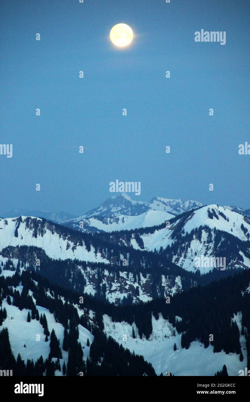 Blick von der Auerspitze in Richtung Norden, der untergehende Mond über die Berge von links nach rechts Benediktenwand (1799m), Setzberg, kurz vor Sonnenaufgang. Europa, Deutschland, Bayern, Oberbayern, Bayrische Alpen, Mangfall Mountains, Spitzingsee Stockfoto