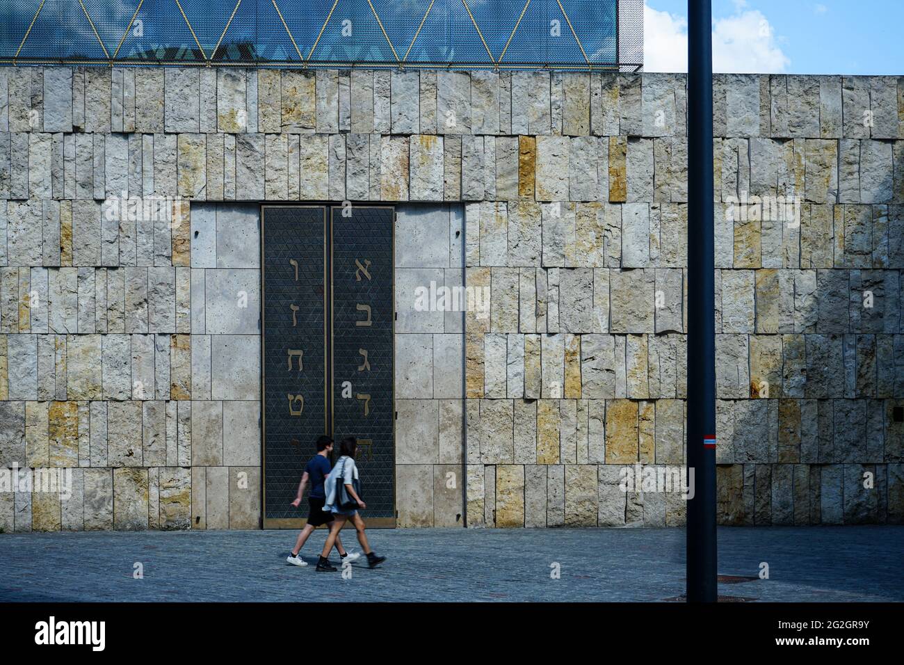 Zwei Männer, die vor der Hauptsynagoge Ohel Jakob am St.-Jakobs-Platz in München neben dem Jüdischen Museum München spazieren. Stockfoto