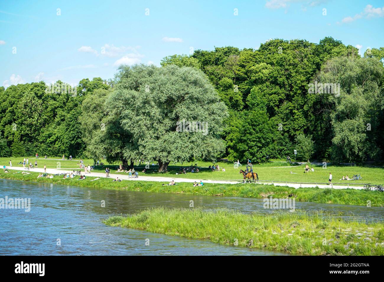 Nach den strengen Corona-Beschränkungen genießen die Menschen das Leben an einem warmen Sommertag am Ufer der Isar in München. Berittene Polizisten patrouillieren am Strand. Stockfoto