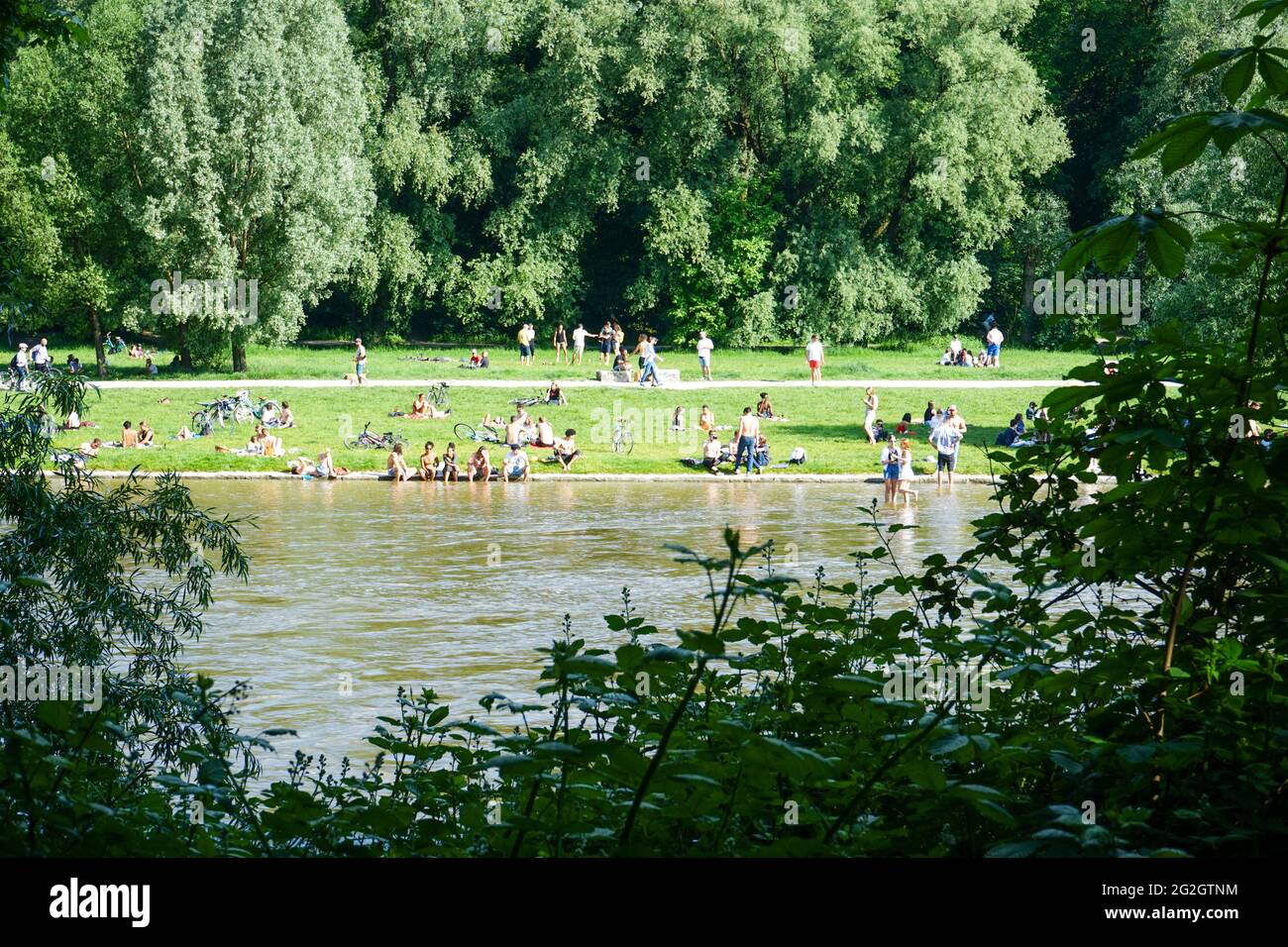 Nach den strengen Corona-Beschränkungen genießen die Menschen das Leben an einem warmen Sommertag am Ufer der Isar in München. Stockfoto