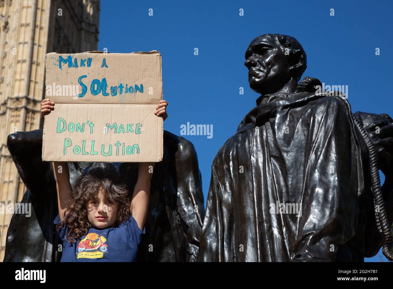 Ein Kind, das gegen den Klimawandel protestiert, auf Auguste Rodins Skulptur „die Bürger von Calais“ in den Victoria Tower Gardens, London. Stockfoto