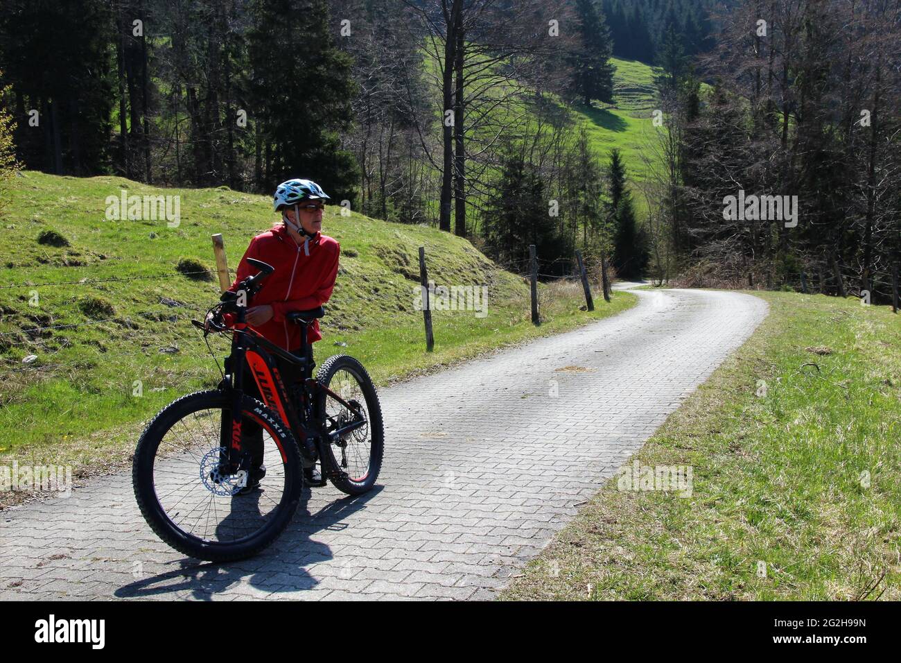 Frau auf einer Fahrradtour mit Mountainbike, E-Bike, E-Bike Deutschland, Bayern, Voralpen, Ohlstadt, Frühling, Straße, Weg, Fahrradhelm, Fahrrad Stockfoto