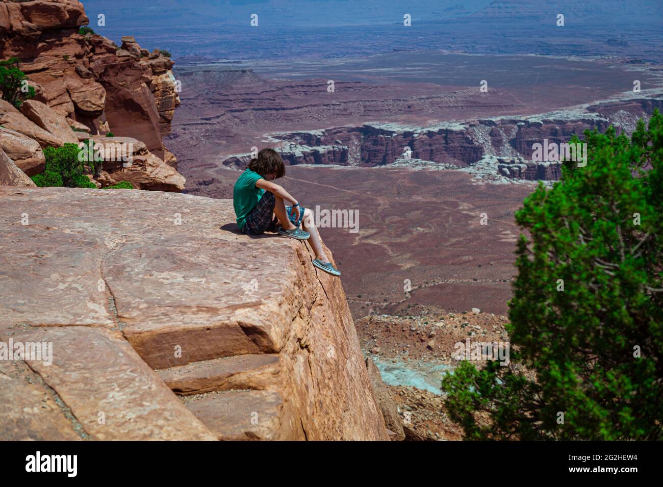 Boy on a Cliff on Grand View Point. Landschaftlich reizvoller Ausziehweg und leichte 2-Meilen-Wanderung entlang des mesa Rim mit atemberaubenden Ausblicken auf das dramatische Canyon-Gelände im Canyonlands National Park, Utah, USA Stockfoto