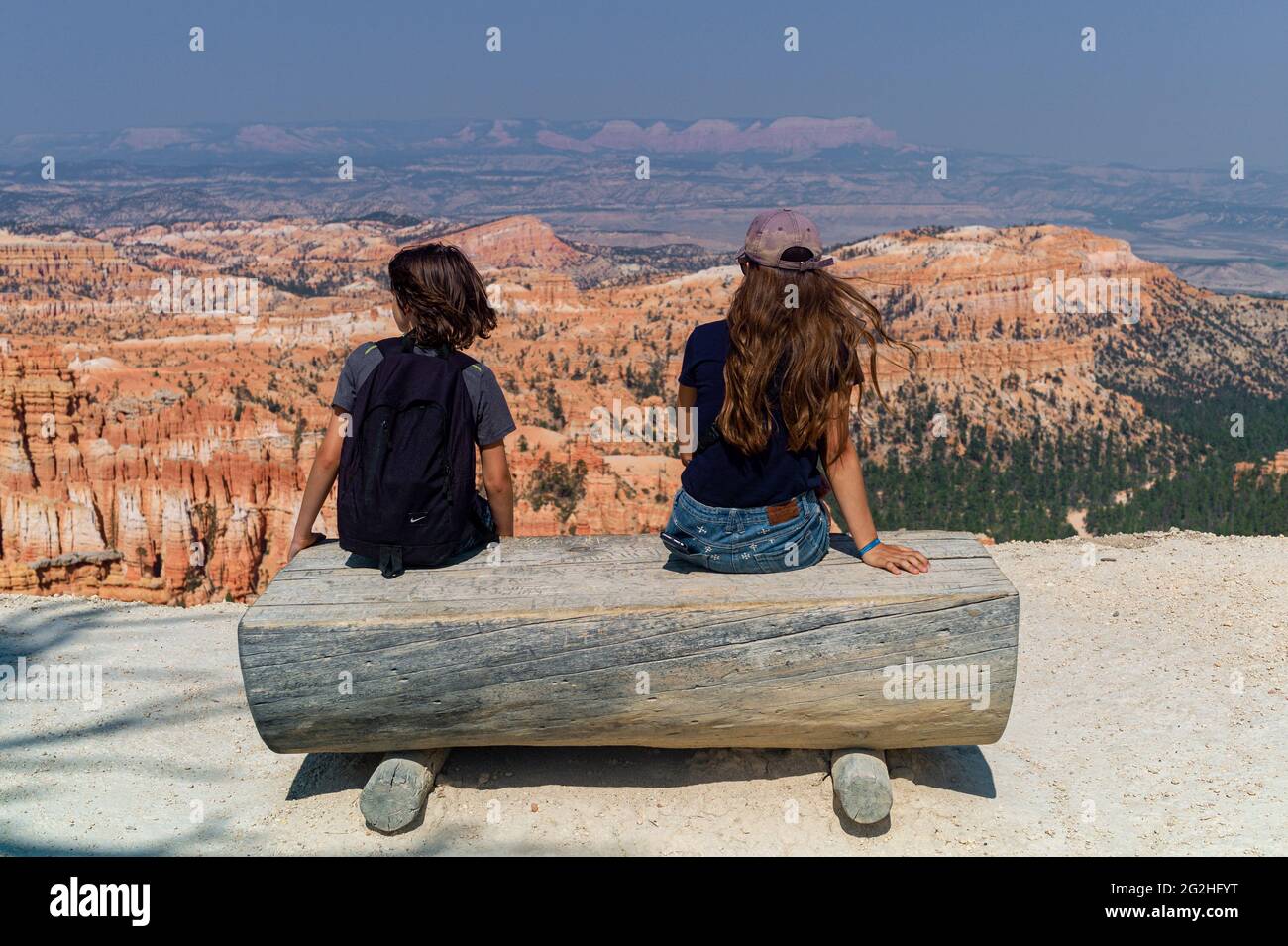 Junge und Mädchen, die am Inspiration Point sitzen und zusehen – einem Aussichtspunkt mit Blick auf den Canyon im Bryce Canyon National Park, Utah, USA Stockfoto