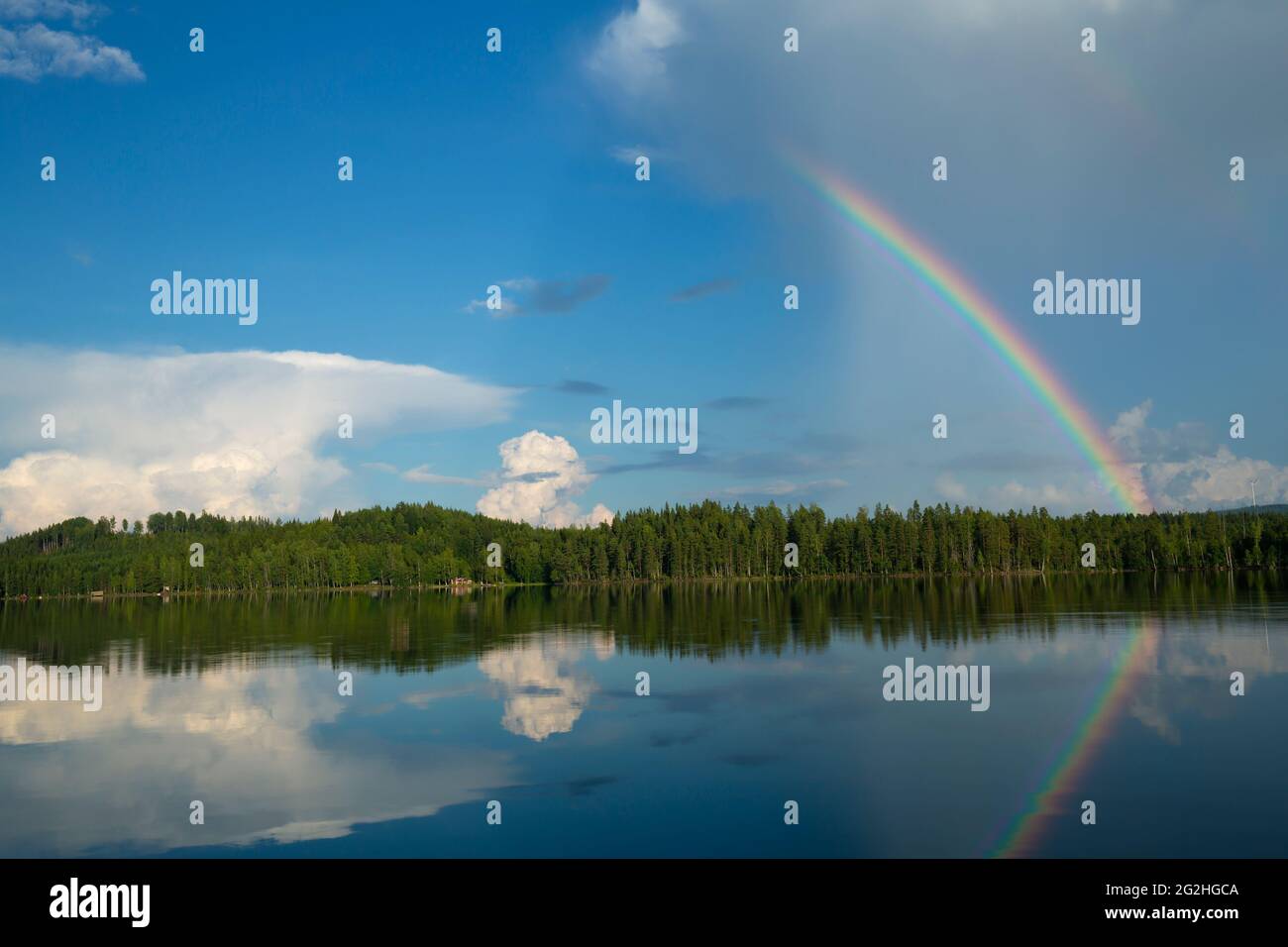 Ruhiger See in schweden mit einem Regenbogen, der sich an der Oberfläche spiegelt Stockfoto