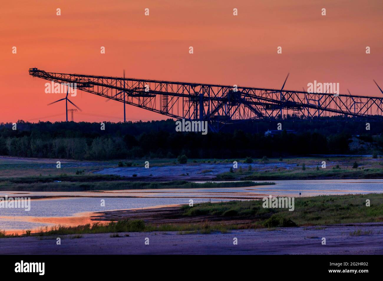 Vergangenheit trifft Zukunft, alte Energie (Braunkohle) trifft neue Energie (Windkraft) - Blick über den Seeteich im Naturparadies Grünhaus zur ehemaligen Überladenförderbrücke F60, südlich von Finsterwalde bei Lichterfeld Stockfoto