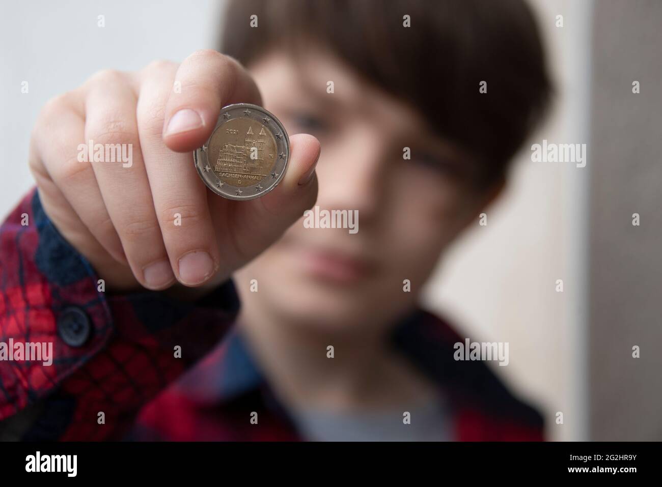 Deutschland, Sachsen-Anhalt, Magdeburg, Junge hält eine 2-Euro-Münze mit Magdeburger Dom in der Hand. Stockfoto