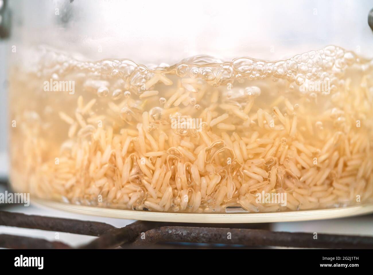 ฺBoiling Reissuppe, schließen Sie sich auf den Boden des Glastöpfels, während Sie Reissuppe kochen, Blasen von Hitze, mit braunem Reis zu kochen. Stockfoto