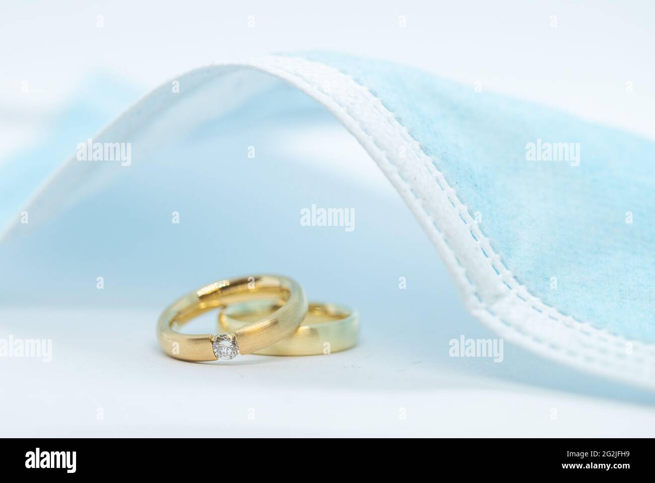 11. Juni 2021, Niedersachsen, Osnabrück: ILLUSTRATION - Trauringe liegen unter einer Mund- und Nasenschutzmaske. Seit Anfang Juni sind Feiern mit mehr Gästen wieder erlaubt. Der Inzidenzwert bestimmt, wie viele Personen teilnehmen dürfen. Nach monatelangen Hoffnungen und Ängsten scheinen die Entspannung Niedersachsens das Heil für Brautpaare zu sein. Aber das bleibt auch weiterhin der Fall. (To dpa: 'Entspannung in Niedersachsen: Aber der Hochzeits-Boom bleibt aus') Foto: Friso Gentsch/dpa Stockfoto