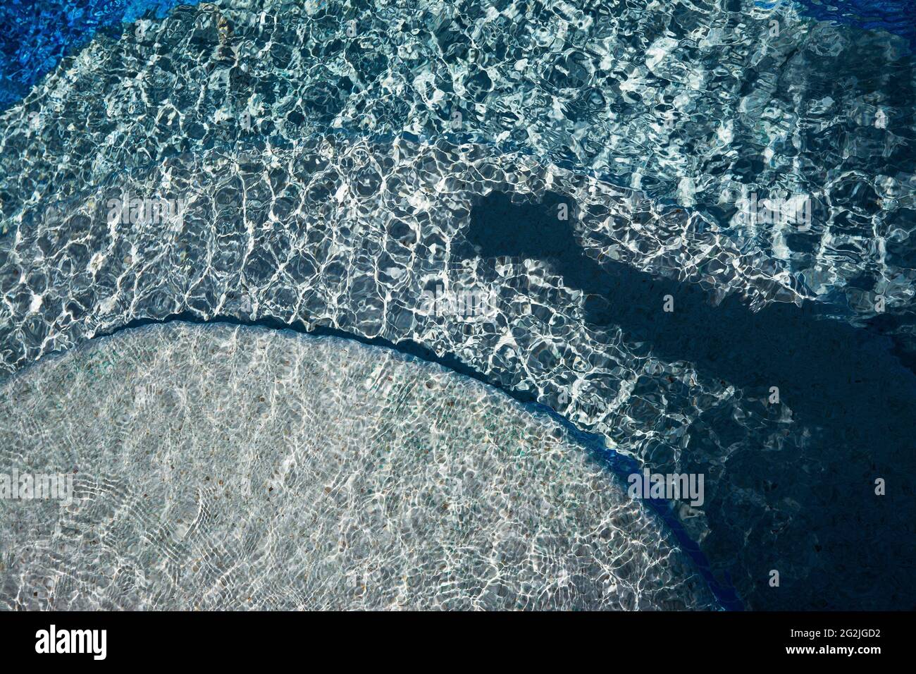 Sommerstimmung, plätschernde Wellen im Pool, Wabenmuster, Schatten zeigt Arm mit Kamera Stockfoto