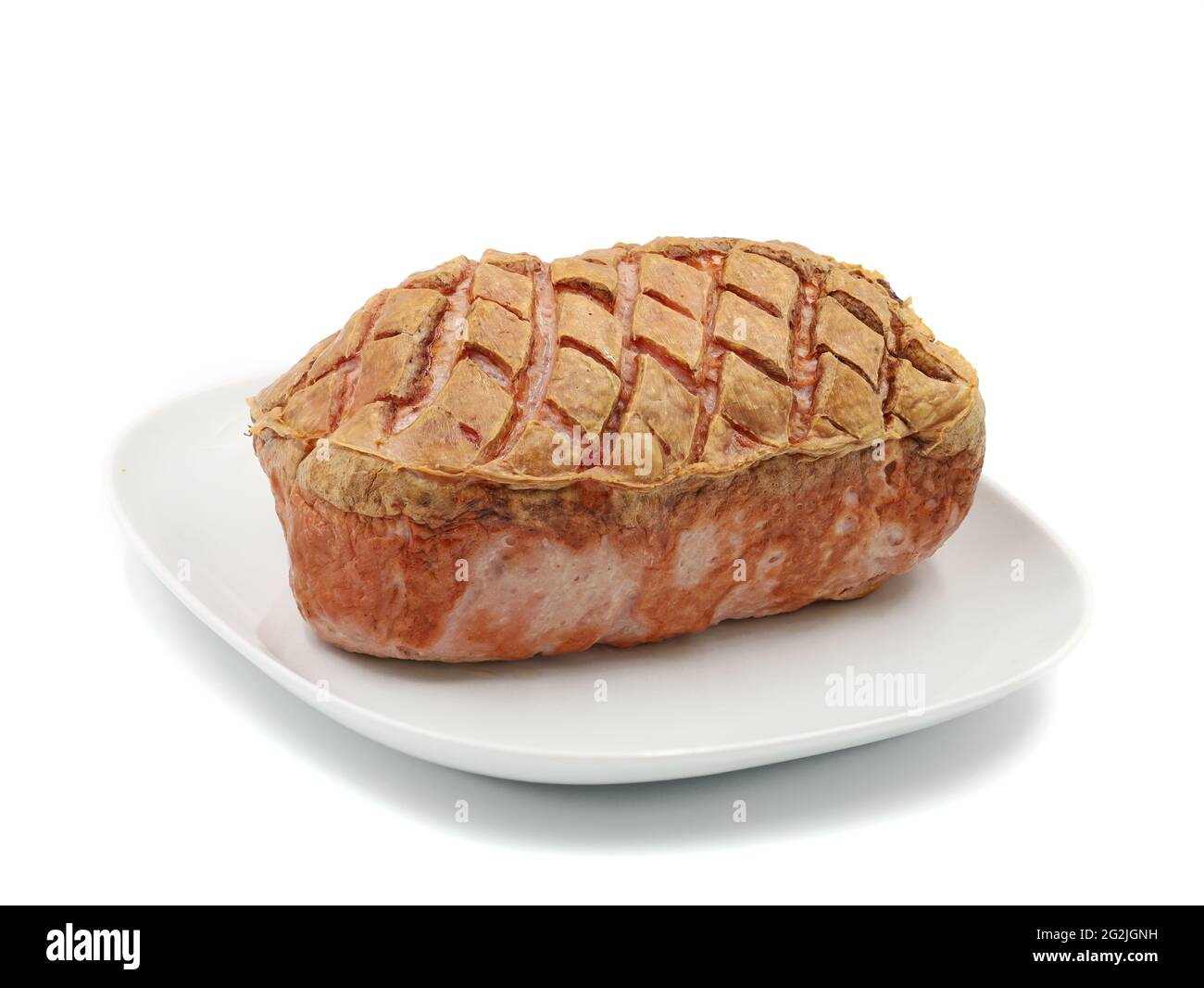 Der ganze traditionelle, warme bayerische Fleischkuchen auf einem weißen Teller wird isoliert auf weißem Hintergrund serviert Stockfoto
