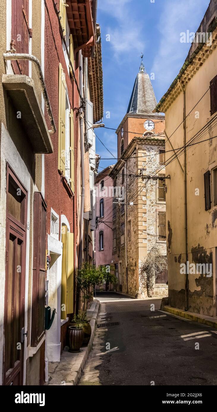 Dorfallee in Saint Chinian mit Blick auf den Glockenturm der Kirche Notre Dame de l'Assomption im Frühjahr. Stockfoto