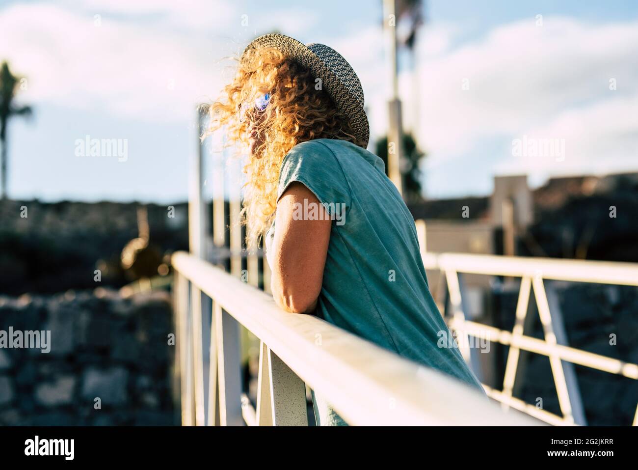 Blonde lange lockiges Haar Frau genießen die Sonne im Freien Freizeitbeschäftigung allein - Konzept der glücklichen Menschen Touristen und Fröhlicher Lebensstil Stockfoto