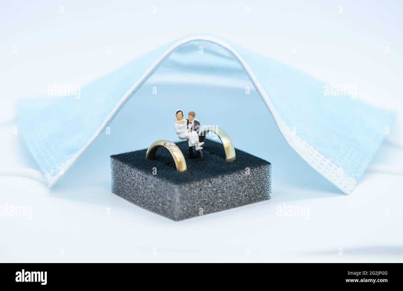 11. Juni 2021, Niedersachsen, Osnabrück: ILLUSTRATION Hochzeitsringe liegen in einer Schachtel unter einer Mund- und Nasenschutzmaske. Seit Anfang Juni sind wieder Feiern mit mehr Gästen erlaubt. Der Inzidenzwert bestimmt, wie viele Personen teilnehmen dürfen. Nach monatelangen Hoffnungen und Ängsten scheinen die Entspannung Niedersachsens das Heil für Brautpaare zu sein. Aber das bleibt auch weiterhin der Fall. (To dpa: 'Entspannung in Niedersachsen: Aber der Hochzeits-Boom bleibt aus') Foto: Friso Gentsch/dpa Stockfoto