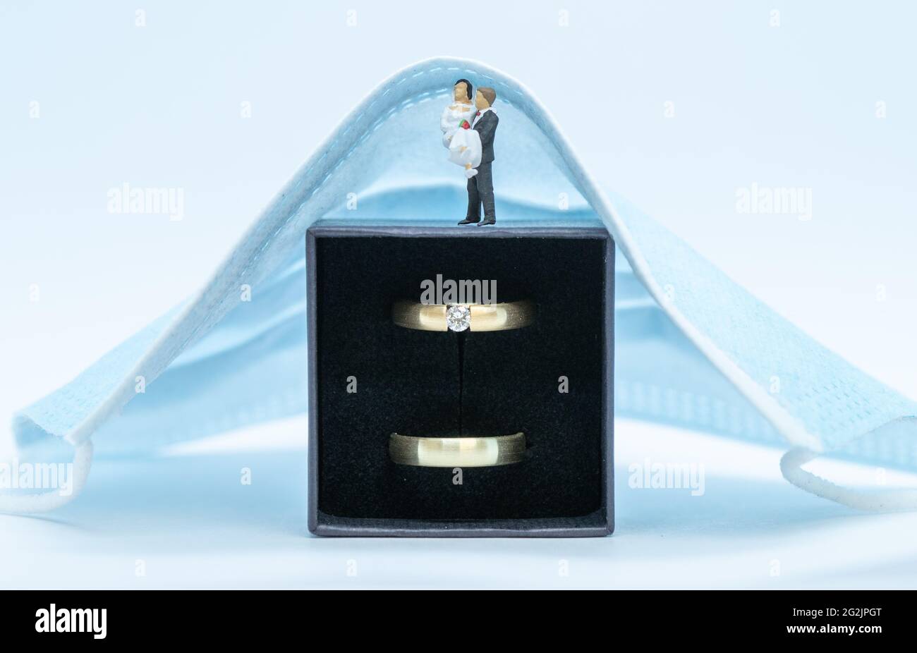 11. Juni 2021, Niedersachsen, Osnabrück: ILLUSTRATION Hochzeitsringe liegen in einer Schachtel unter einer Mund- und Nasenschutzmaske. Seit Anfang Juni sind wieder Feiern mit mehr Gästen erlaubt. Der Inzidenzwert bestimmt, wie viele Personen teilnehmen dürfen. Nach monatelangen Hoffnungen und Ängsten scheinen die Entspannung Niedersachsens das Heil für Brautpaare zu sein. Aber das bleibt auch weiterhin der Fall. (To dpa: 'Entspannung in Niedersachsen: Aber der Hochzeits-Boom bleibt aus') Foto: Friso Gentsch/dpa Stockfoto