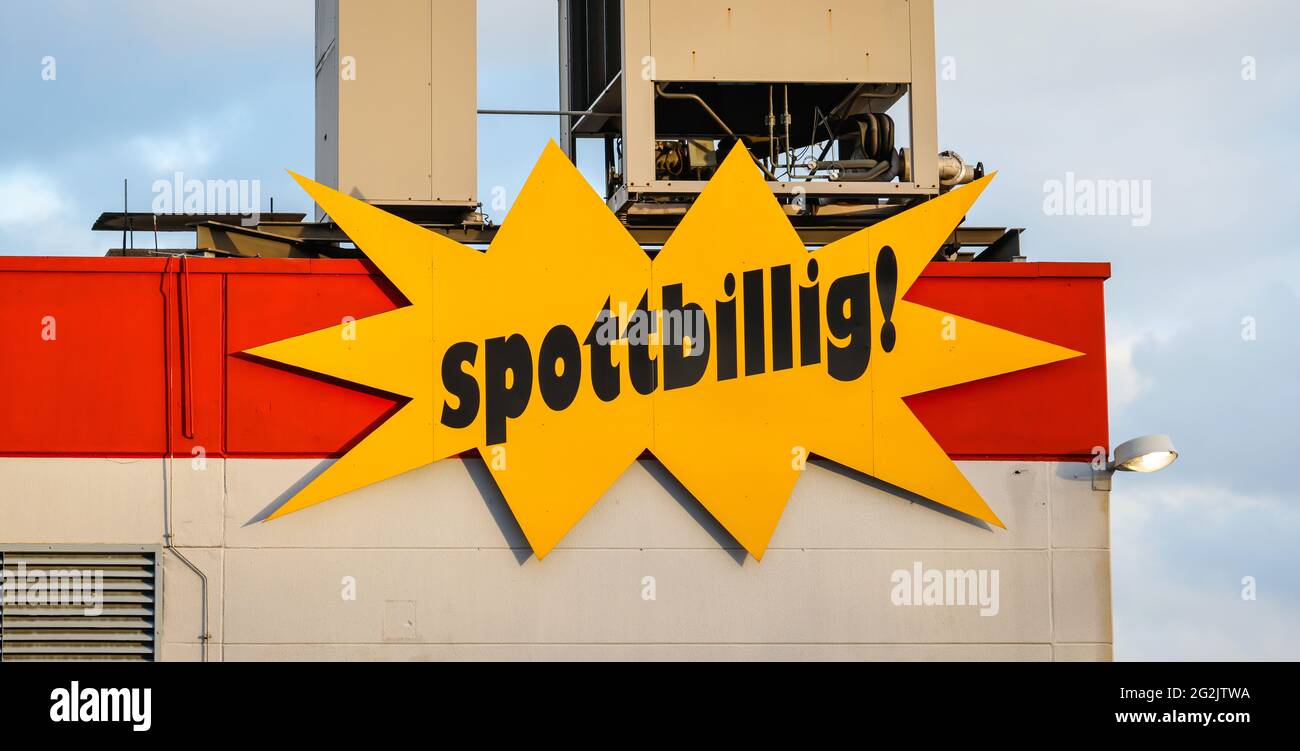 Mülheim, Nordrhein-Westfalen, Deutschland - schmutzbillig, Schriftzug auf der Fassade eines Spezialartikelmarktes vor bewölktem Himmel. Stockfoto