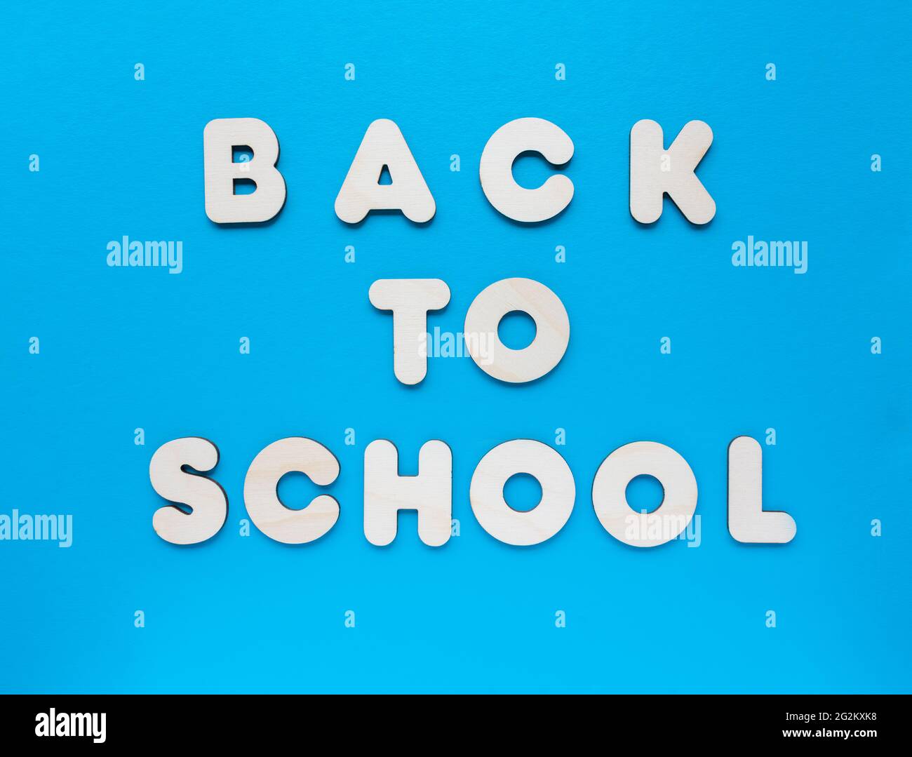 Inschrift ZURÜCK ZUR SCHULE aus Holzbuchstaben auf blauem Hintergrund. Das Konzept der Bedeutung von Bildung. Stockfoto